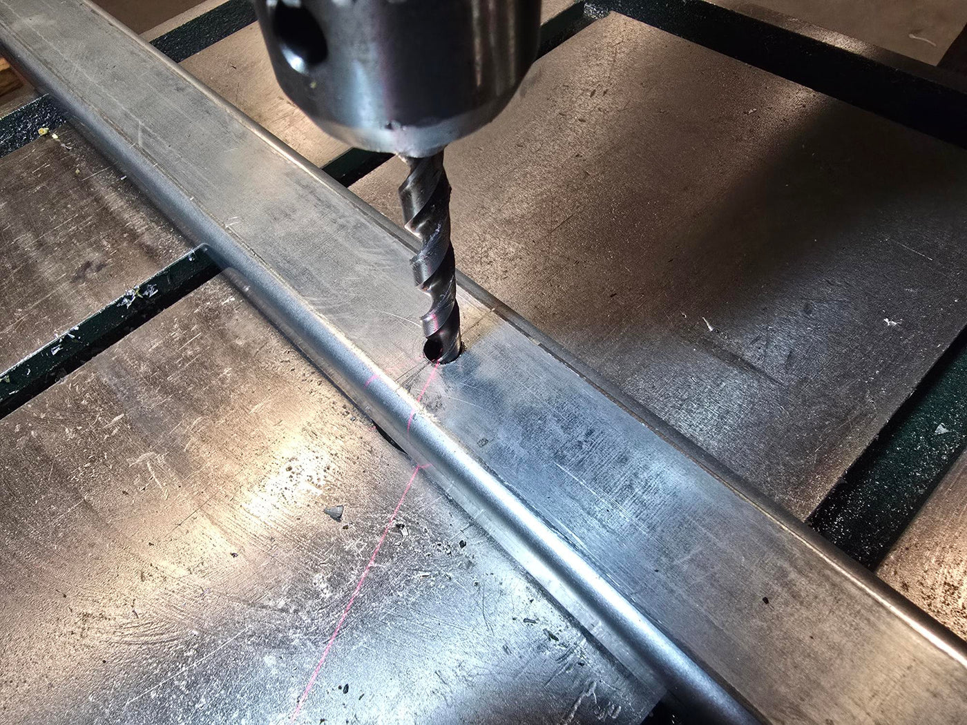 Drill bit making a hole in metal on a workbench